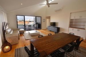 a living room with a wooden table and a kitchen at The Carnarvon Luxury Canal Home in Carnarvon