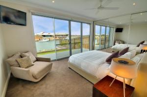 um quarto com uma cama, um sofá e uma janela grande em The Carnarvon Luxury Canal Home em Carnarvon