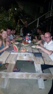 a large group of people sitting around a wooden table at Go Slow Guesthouse in Caye Caulker