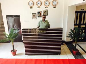 un hombre parado detrás de una recepción en una habitación con relojes en Hotel Dharohar Palace, en Jaipur