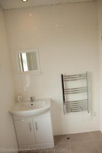 a white bathroom with a sink and a mirror at Home from Home in Ilford