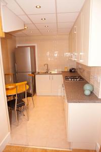 a kitchen with white cabinets and a table and a refrigerator at Home from Home in Ilford
