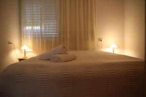 a bedroom with a large white bed with two lamps at Kinneret Guesthouse in Neot Golan
