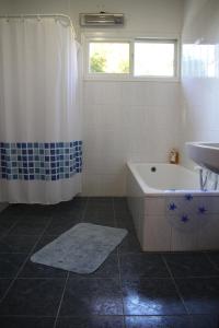 y baño con bañera y lavamanos. en Kinneret Guesthouse, en Neot Golan