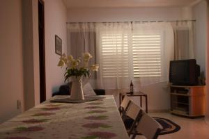a dining room table with a vase of flowers on it at Kinneret Guesthouse in Neot Golan