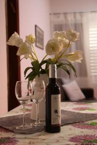 a bottle of wine and two glasses on a table with flowers at Kinneret Guesthouse in Neot Golan