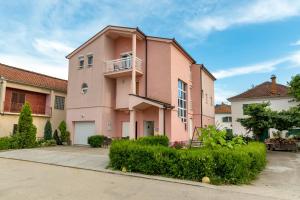 a pink house with a balcony in a yard at Arenta Apartments in Metković