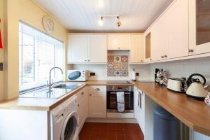 a kitchen with white cabinets and a sink and a dishwasher at Ceilidh Cottage in York