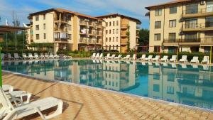a large swimming pool with lounge chairs and buildings at Nestinarka Complex - Emili Apartment in Tsarevo