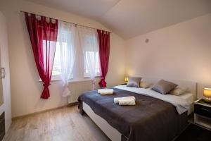 a bedroom with a large bed with red curtains at Arenta Apartments in Metković
