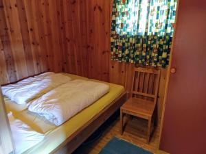 uma cama e uma cadeira num quarto com paredes de madeira em Hogstul Hytter - Apartment South em Tuddal