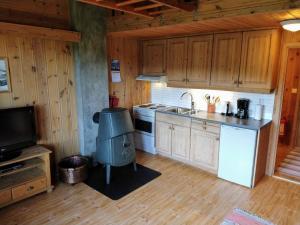 a kitchen with wooden cabinets and a stove top oven at Hogstul Hytter - Apartment South in Tuddal