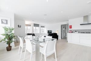 uma sala de jantar branca com uma mesa de vidro e cadeiras brancas em Roomspace Serviced Apartments- Walpole Court em Ealing