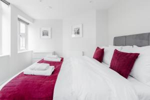 a white bedroom with a large bed with red blanket at Roomspace Serviced Apartments- Walpole Court in Ealing