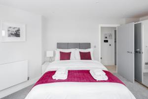 a white bedroom with a large bed with red pillows at Roomspace Serviced Apartments- Walpole Court in Ealing
