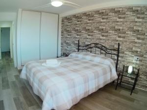 a bedroom with a bed and a brick wall at Marqués de Comillas II in Benidorm