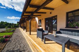 a wooden deck with couches and tables on a house at Apartamenty Wiatr i Woda in Mikołajki