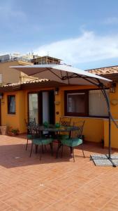 patio con tavolo, sedie e ombrellone di Attico Sole Luna a Taormina