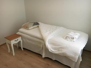 a small bed with white sheets and a night stand at Bästlandia Apartments with Sauna in Vaasa +14 photos