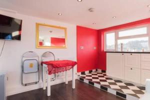 eine rote Küche mit einem Tisch und einem karierten Boden in der Unterkunft Studio flat 15 min from Greenwich ( en-suite) in Plumstead