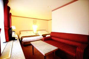 ein Hotelzimmer mit einem Sofa und 2 Betten in der Unterkunft Arrow Hotel in ShinsaiBashi 朝食無料サービス中 in Osaka