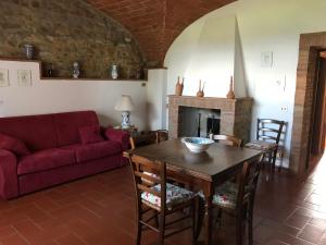 sala de estar con mesa y sofá rojo en La Casina Rosella, en Montaione
