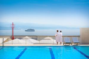two people standing next to a swimming pool at Hotel Admiral - by Liburnia Hotels & Villas in Opatija