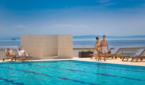 a group of people standing next to a swimming pool at Hotel Admiral - by Liburnia Hotels & Villas in Opatija
