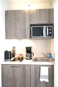 a kitchen with a sink and a microwave at Domitys Paris Plaisance in Paris