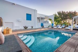 a swimming pool with chairs and a house at Eiriana Luxury Suites in Plaka Milou