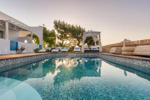 a swimming pool with chairs and a house at Eiriana Luxury Suites in Plaka Milou