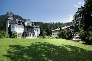 a large house on a hill with a large grass field at Hotel Seewinkel in Fuschl am See