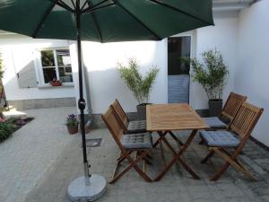 ein Tisch und Stühle unter einem Sonnenschirm auf einer Terrasse in der Unterkunft Cottage Ferienwohnung mit Seeblick in Caputh