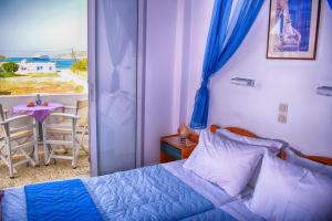 a bedroom with a bed and a view of a beach at Hotel Helena in Ios Chora