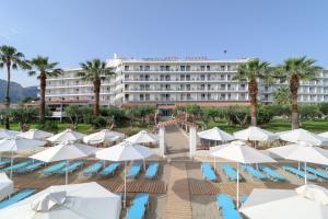 a hotel with a pool and umbrellas and palm trees at Calamos Beach Family Club in Kalamos