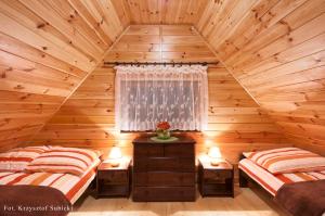 two beds in a log cabin bedroom with two lamps at Domki letniskowe IWET in Darłowo