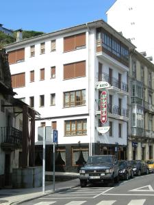 un edificio blanco con coches estacionados frente a él en Hotel Rico en Luarca