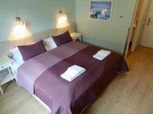 a bedroom with a purple bed with two towels on it at Hali Country Hotel in Gerdi