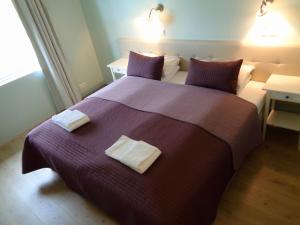 a bedroom with a purple bed with two towels on it at Hali Country Hotel in Gerdi
