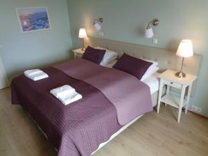 a bedroom with a purple bed with two towels on it at Hali Country Hotel in Gerdi