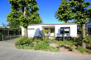 ein weißes Haus mit Bäumen davor in der Unterkunft Bungalow am Schmachter See by Rujana in Binz