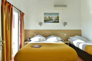 a hotel room with two beds and a window at Mas de la Grenouillère Hôtel et Centre équestre en pleine nature in Saintes-Maries-de-la-Mer