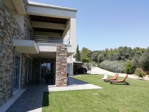 a house with two chairs sitting on the lawn at Dimitra in Rafina