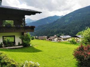 a house in a green field with mountains in the background at Ferienwohnungen Wilhelmer in Liesing