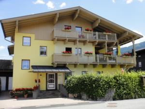a yellow house with balconies and flowers on it at Appartement Holiday + Villa Theresa in Kaprun
