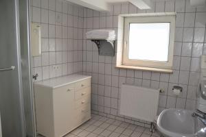 金茨堡Gästehaus Kirchenbauerhof的白色瓷砖浴室设有水槽和窗户