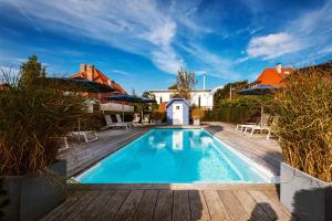a swimming pool with a wooden deck next to a house at Romantik B&B Zonnehuis in De Haan