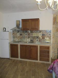 a kitchen with wooden cabinets and a tile wall at Korina Studios in Paleokastritsa