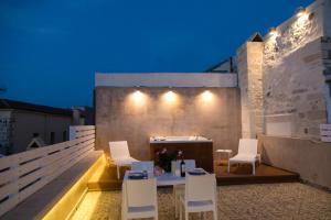 a patio with white chairs and a table and lights at Jacuzzi Suite In The Heart Of OldTown in Rethymno