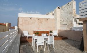 a patio with white chairs and a table on a roof at Jacuzzi Suite In The Heart Of OldTown in Rethymno